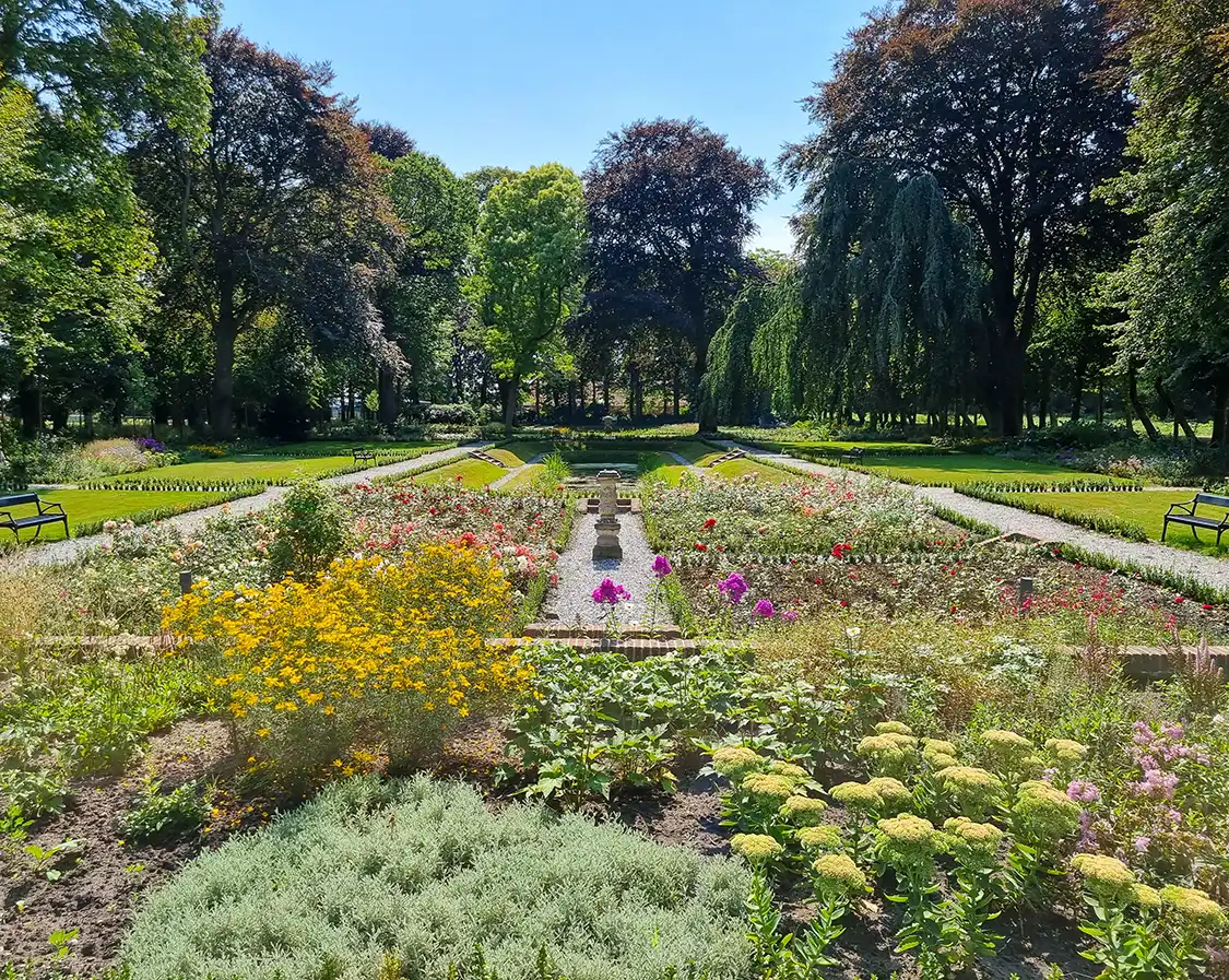 Aangelegde tuin bij erfgoed met kleurrijke bloemen en bomen op de achtergrond