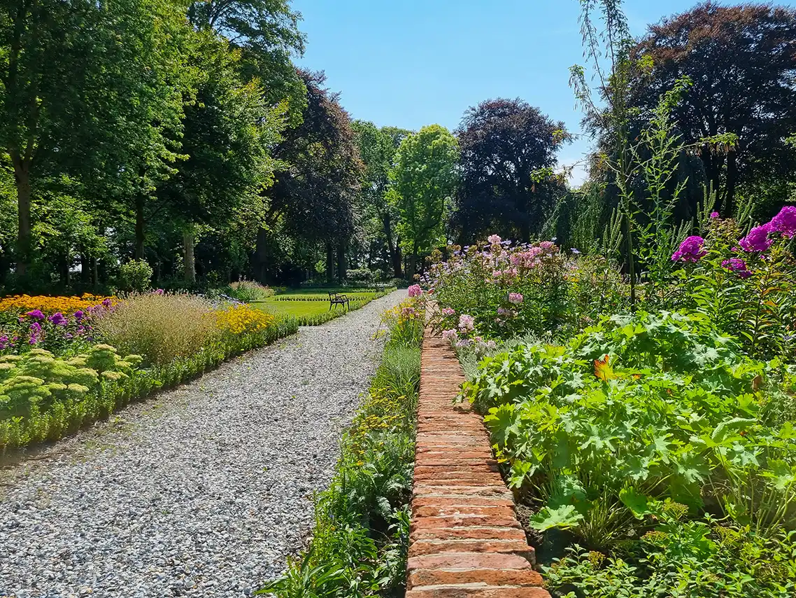 Border bij een erfgoed met veel kleurrijke bloemen en bomen op de achtergrond
