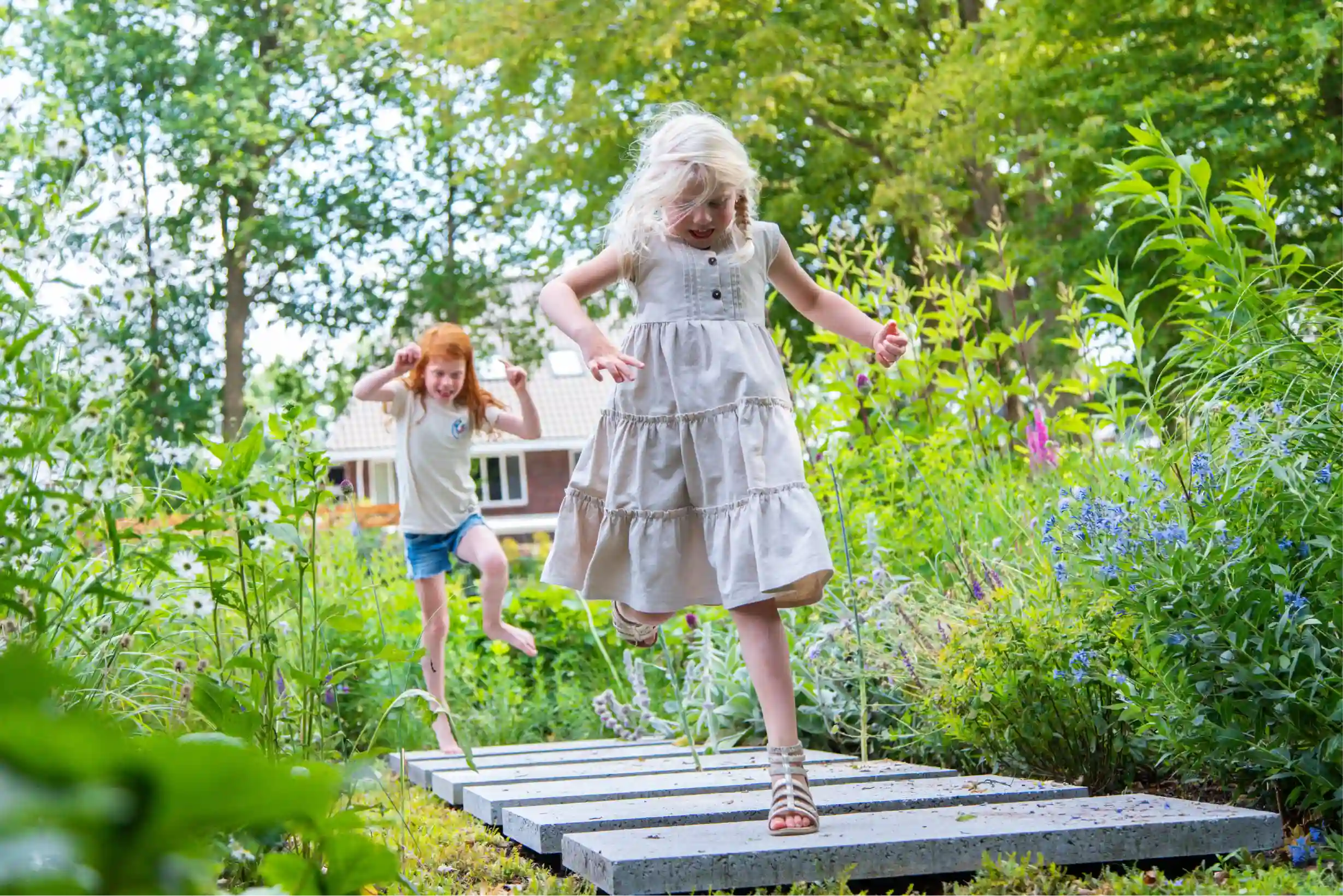 Twee meisjes die aan het spelen zijn in een groene leefruimte als tuin